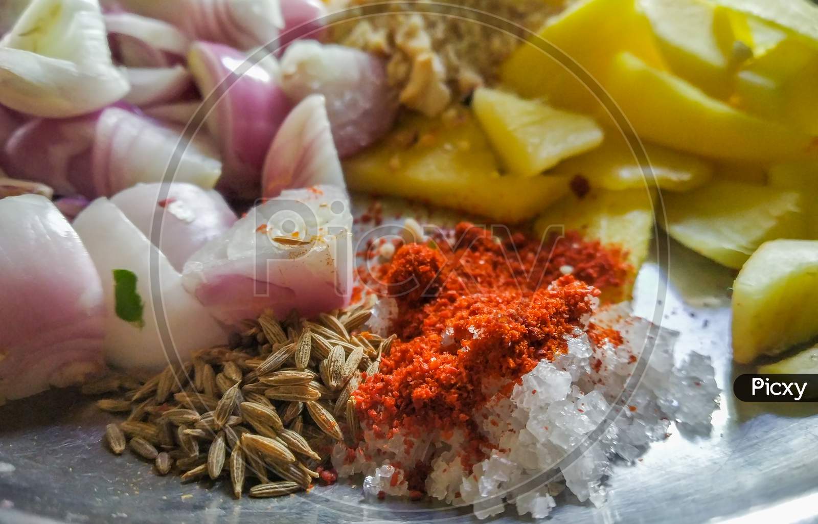 Combined Indian Spices And Ingredients For Making Curry In A Steel Plate With Wooden Background.