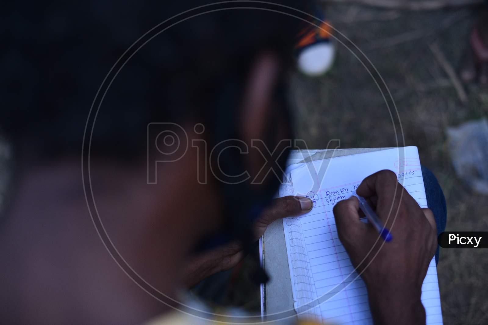 a Migrant worker writes down the names and phone numbers in a paper to get permission to travel till their native states.