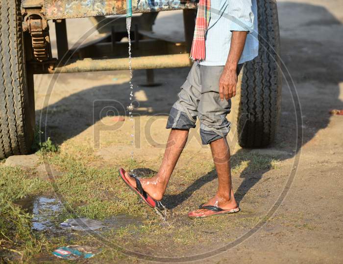 A Migrant Worker Washing His Legs At a Water Tank Arranged by Authorities At Border Checkpost in Aswaraopeta , Telangana
