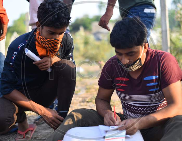 Migrant workers from West Bengal and Bihar write down their Aadhar details in a paper as they wait for permission to cross Telangana State at a Checkpost in Aswaropeta during an extended lockdown amid coronavirus fears, May 16,2020.