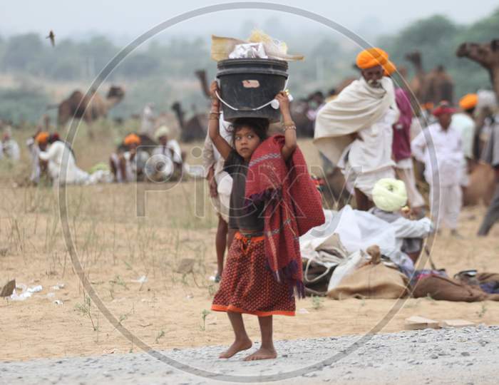 Girl Child Carrying Heavy Weight Over Head At Pushkar Camel Fair, Rajasthan