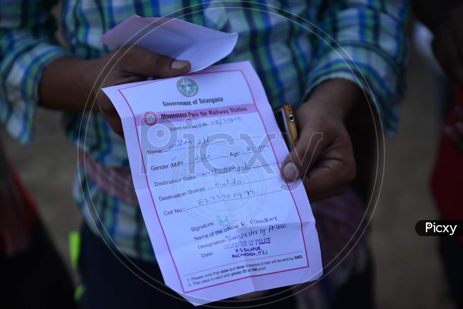A migrant worker shows a movement pass for a railway station issued by Government of Telangana. However, these workers are sent by road in a Van.