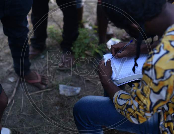 Migrant workers from Bihar write down their names and aadhar details in a paper in order to get permission to travel to their state at Telangana-Andhra Pradesh border, Aswaraopet,Telangana, 16 May, 2020