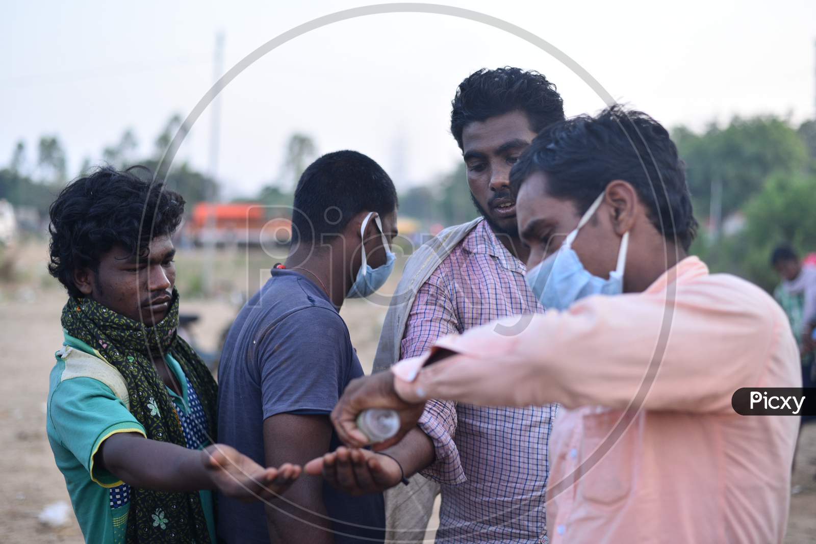 Migrant workers sanitize their hands as they wait at TS-AP Border to get a permission letter to travel across states to reach their hometown in Bihar, May 16,2020, Aswaraopet, Telangana