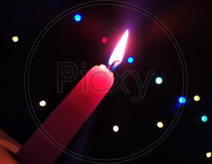 A CANDLE FLAME GIVE LIGHT IN DARK NIGHT WITH LIGHT BILINKING BEHIND