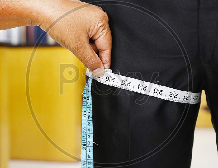 Closeup tailor hand use measuring tape to measure width of jeans