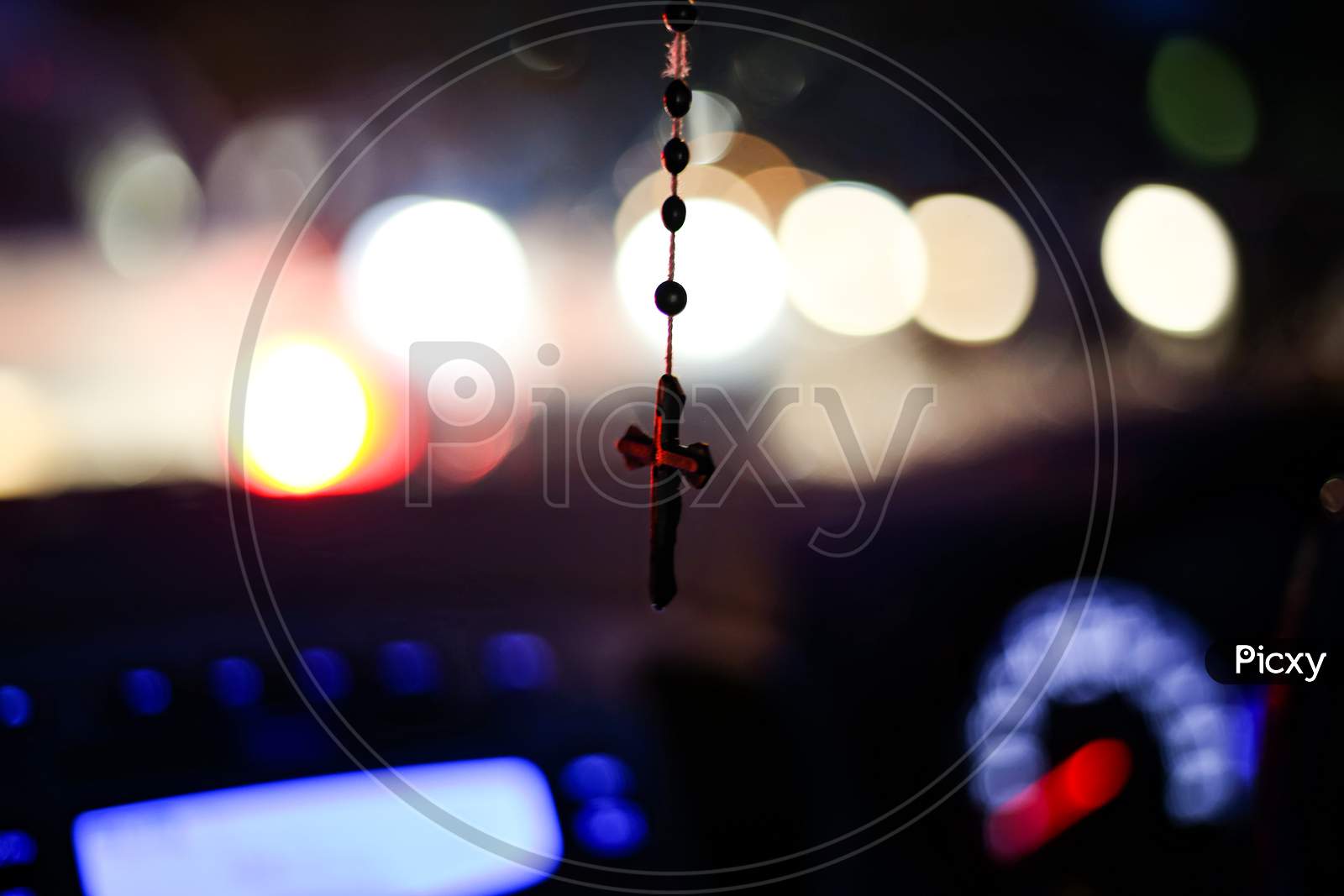 Rosary With Cross Focused And Hanging From Center Mirror Inside The Car, Rest Keeping Everything Defocused