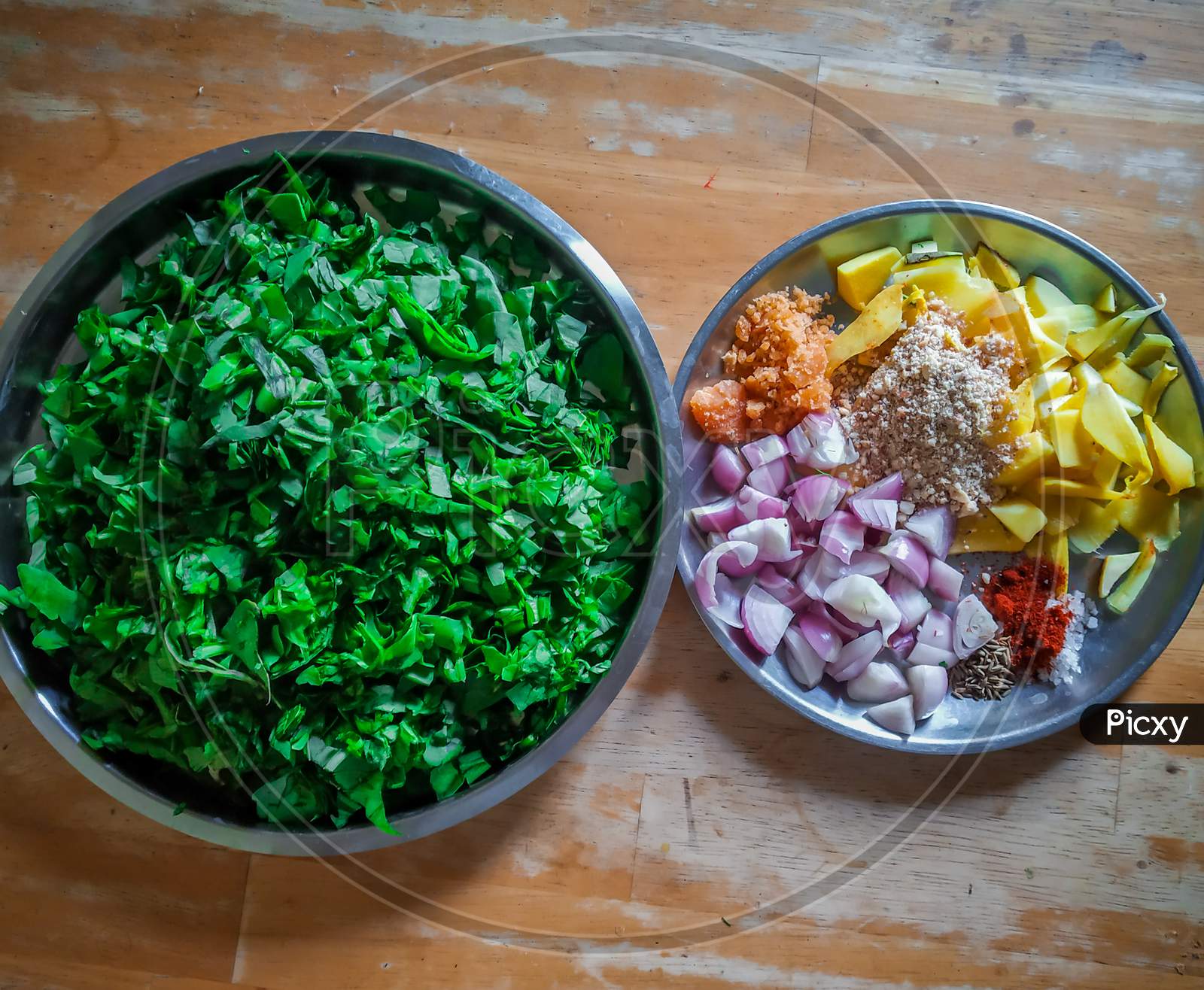 Combined Indian Spices And Ingredients For Making Spinach Curry ( Indian Cuisine ) In A Steel Plate With Wooden Background.