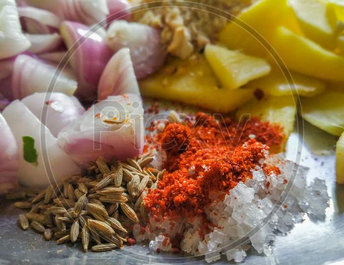 Combined Indian Spices And Ingredients For Making Curry In A Steel Plate With Wooden Background.