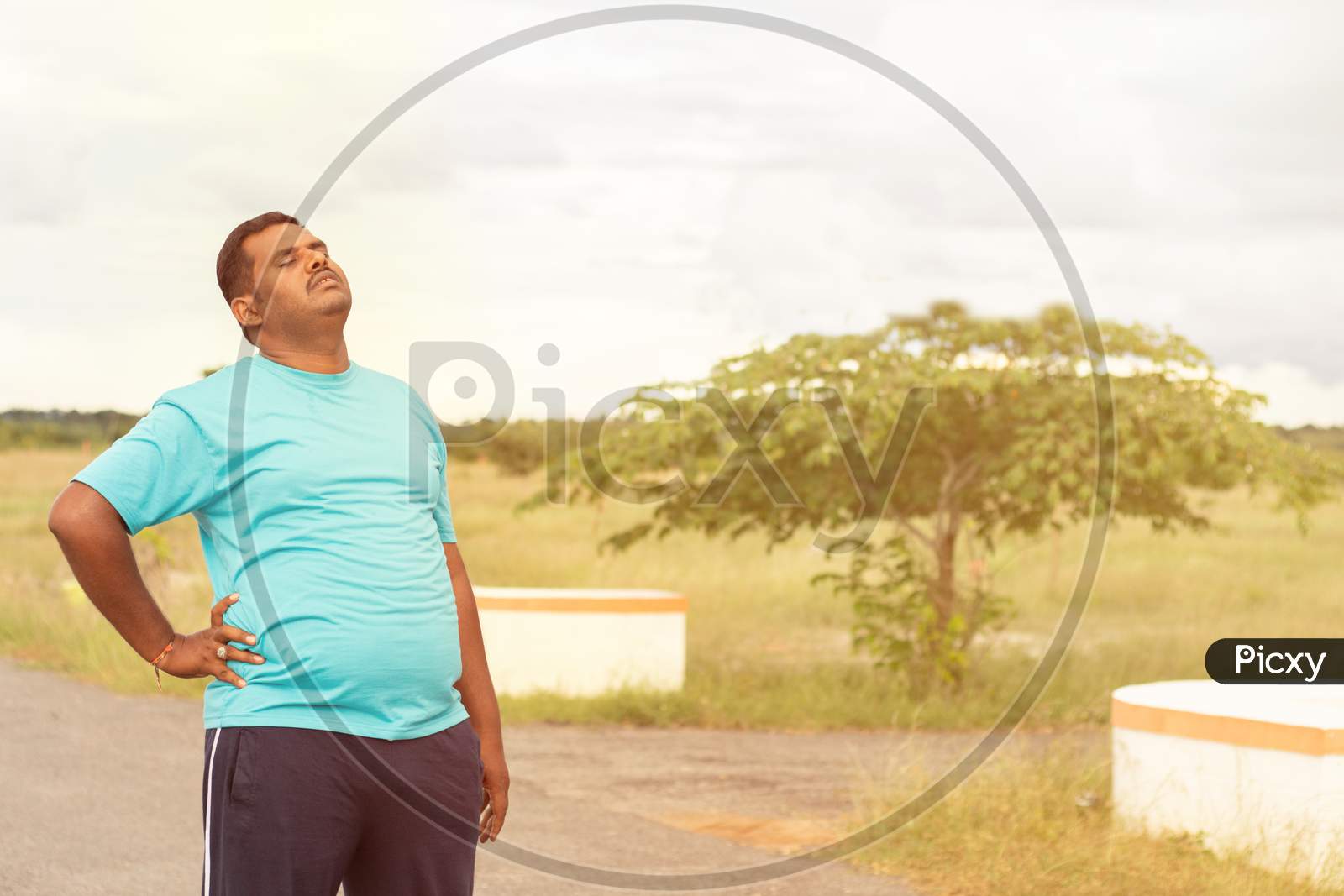 Image of Tired Young Obese Man Holiding His Back While Jogging - Concept Of Fat  Man Fitness And Unhealthy Lifestyle.-AM939054-Picxy