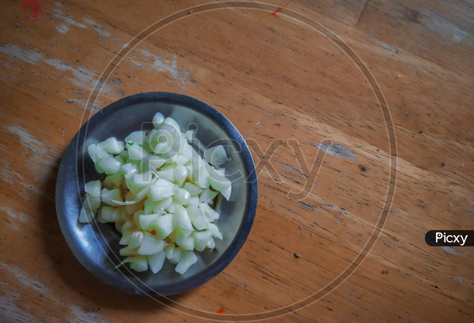 Finely Chopped Garlic In A Steel With Wooden Background.