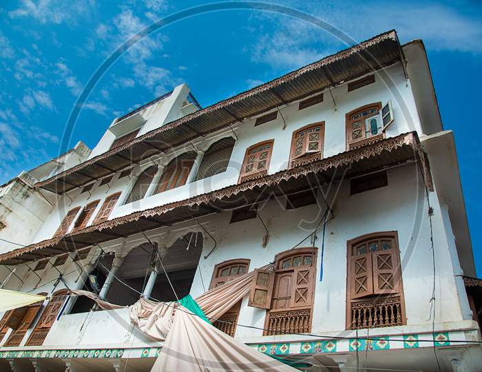 Pushkar, Rajasthan, India - Oct 6, 2019: Traditional House Architecture Of A White Building With Many Wooden Doors And Windows Against Blue Sky, Architectural Concept.