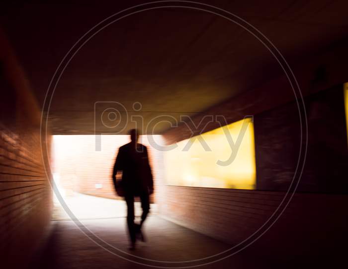 Silhouette In Movement Of A Human Figure Walking Through A Tunnel