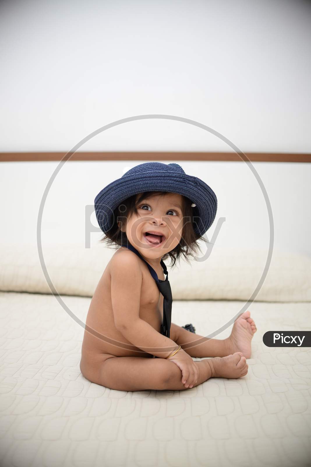 Baby smiling, wearing a hat and a tie
