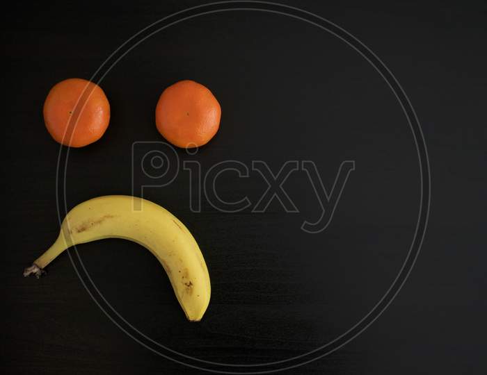 Sad Face Made Out Of Fruits On Black Background
