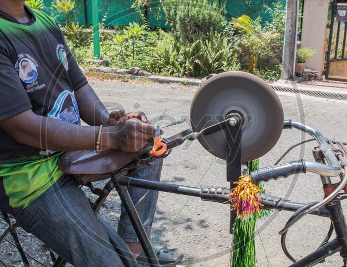 Side View Of A Guy Sharpening Tools On His Bicycle