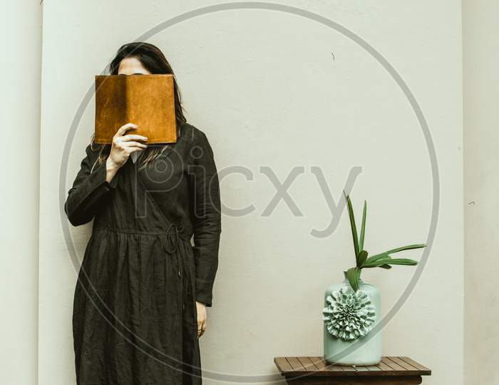 Girl hiding face with a book