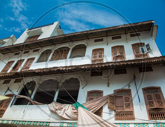 Pushkar, Rajasthan, India - Oct 6, 2019: Traditional House Architecture Of A White Building With Many Wooden Doors And Windows Against Blue Sky, Architectural Concept.