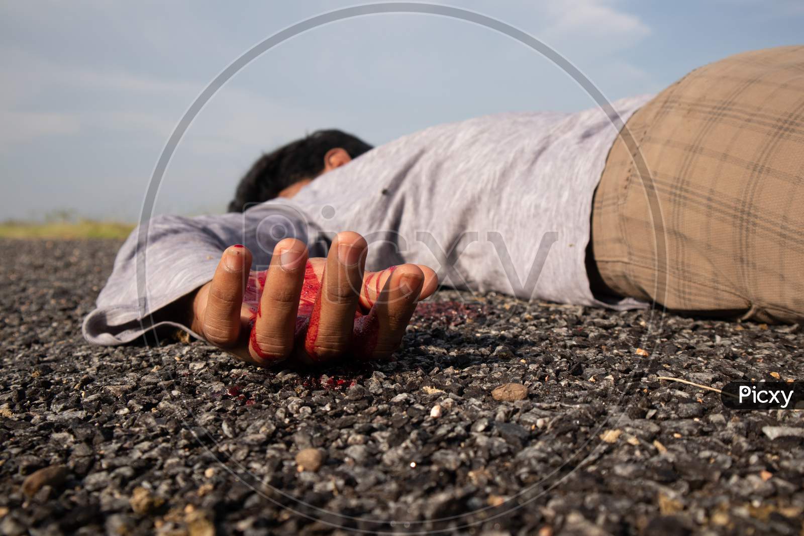 Concept Of Crime Scene ,Selective Focus To Victim Hand With Blood Of A Dead Body Laying On Road