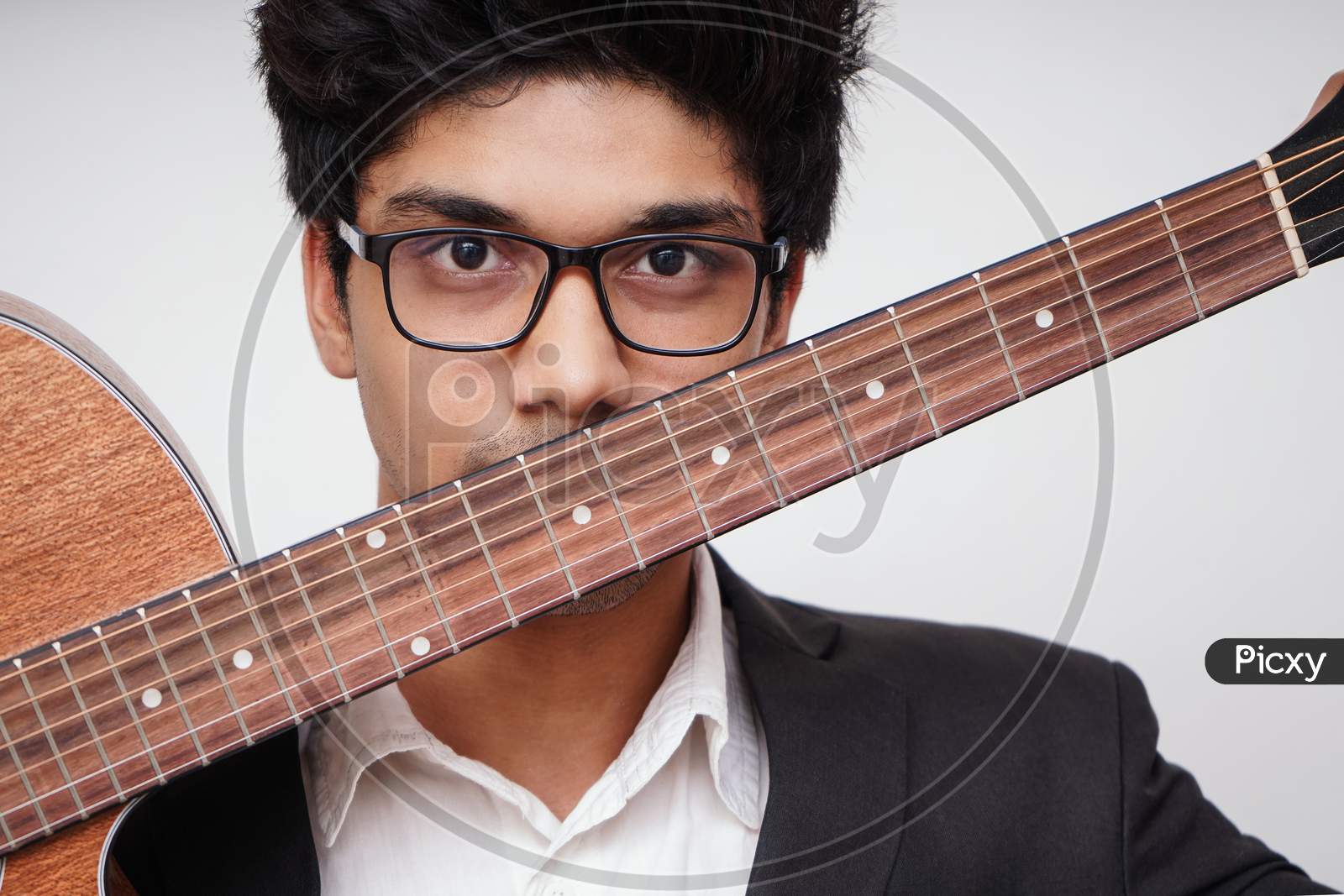 Close Up Of Young Handsome Asian Boy Wearing Formal And Specs Holding A Guitar In Front Of His Face