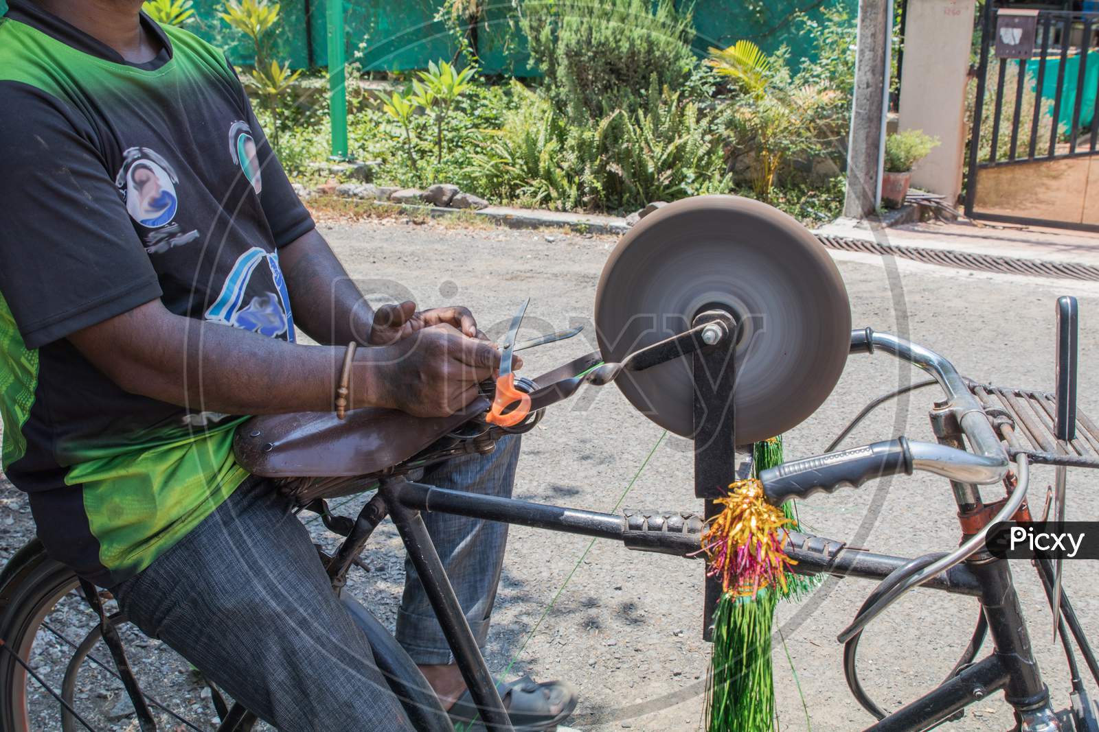 Side View Of A Guy Sharpening Tools On His Bicycle