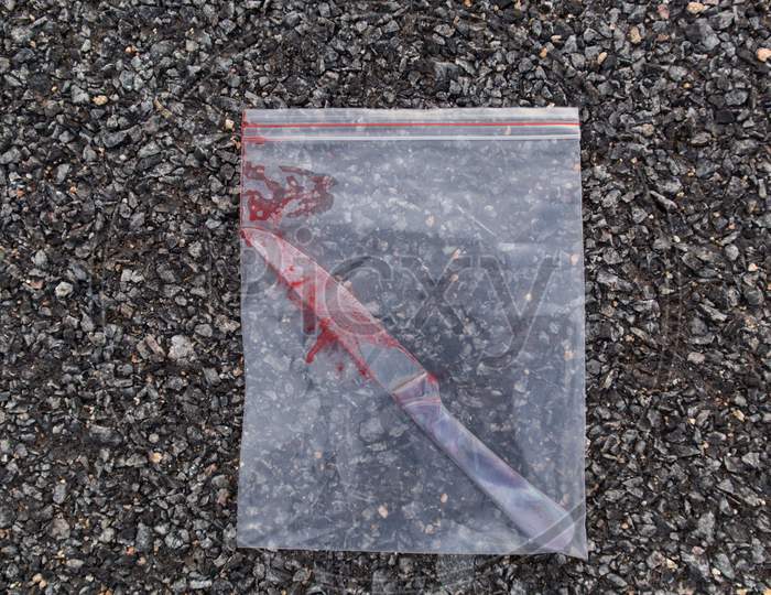 Bloody Knife In Plastic Or Evidence Bag On Road