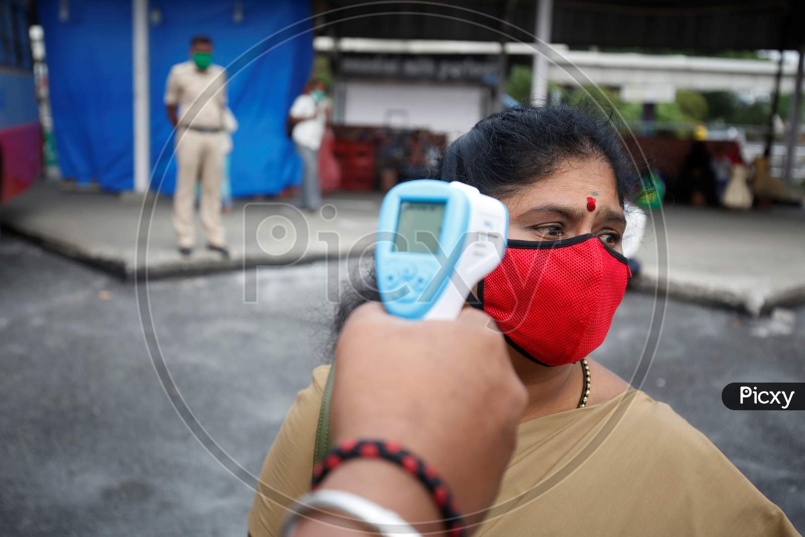 A woman gets her temperature checked before boarding a public transport bus after the state eased lockdown norms during the nationwide lockdown to prevent the spread of coronavirus (COVID-19) in Bangalore, India.