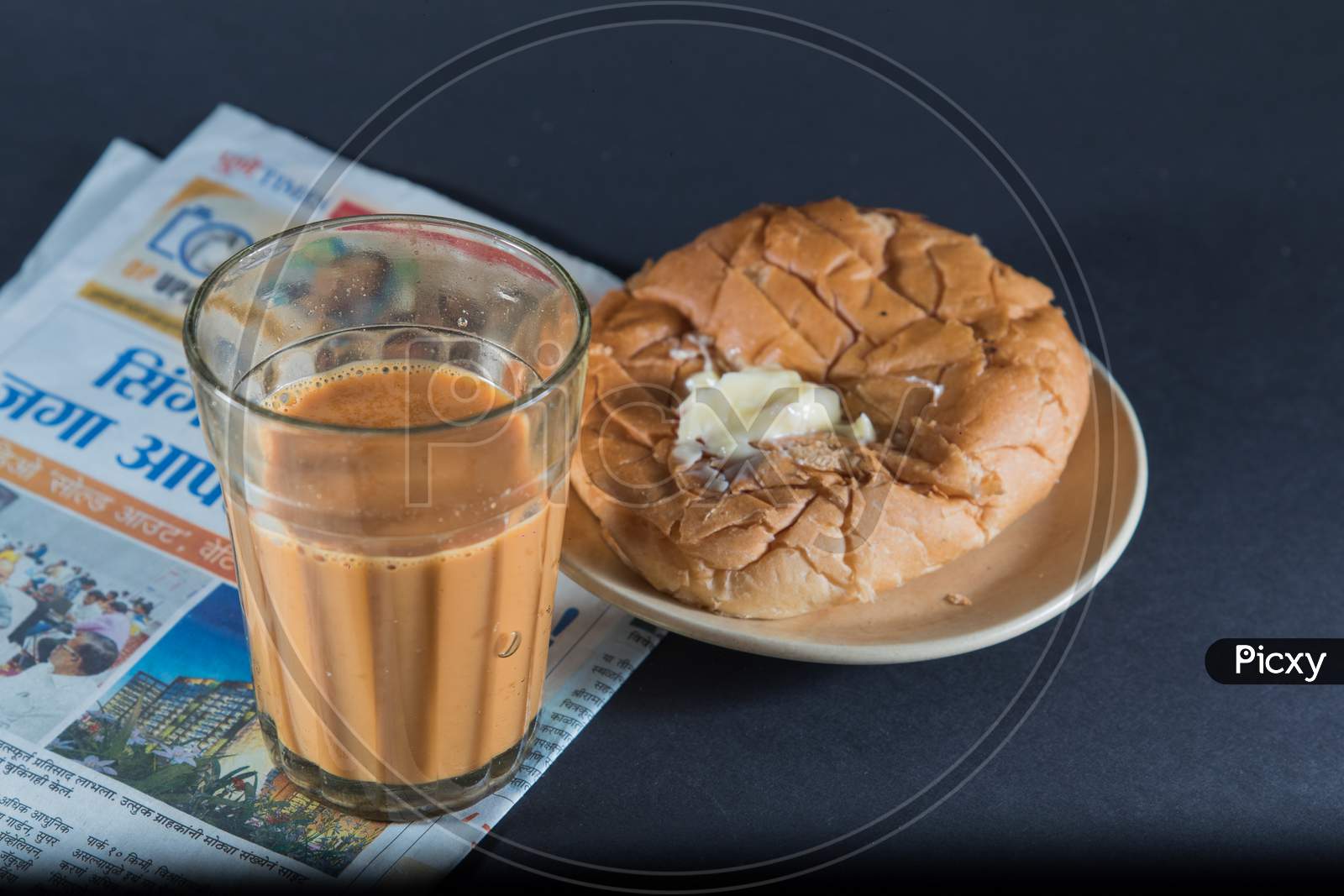 Favorite Indian Breakfst With Tea And Bun Butter Against Black Background