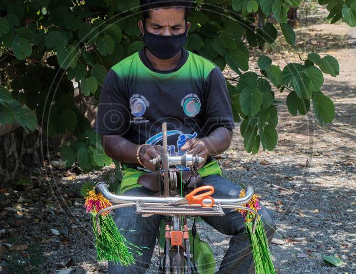 Front View Of A Guy Sharpening Tools On His Bicycle