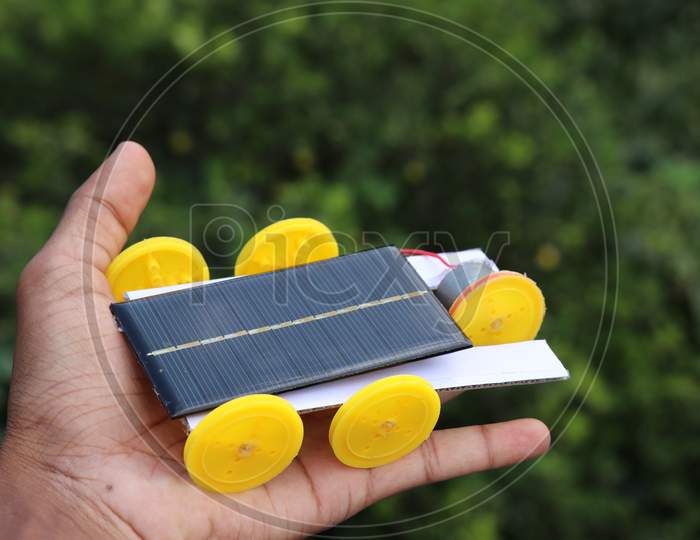 Solar Powered Car With Five Wheels Held In Hand