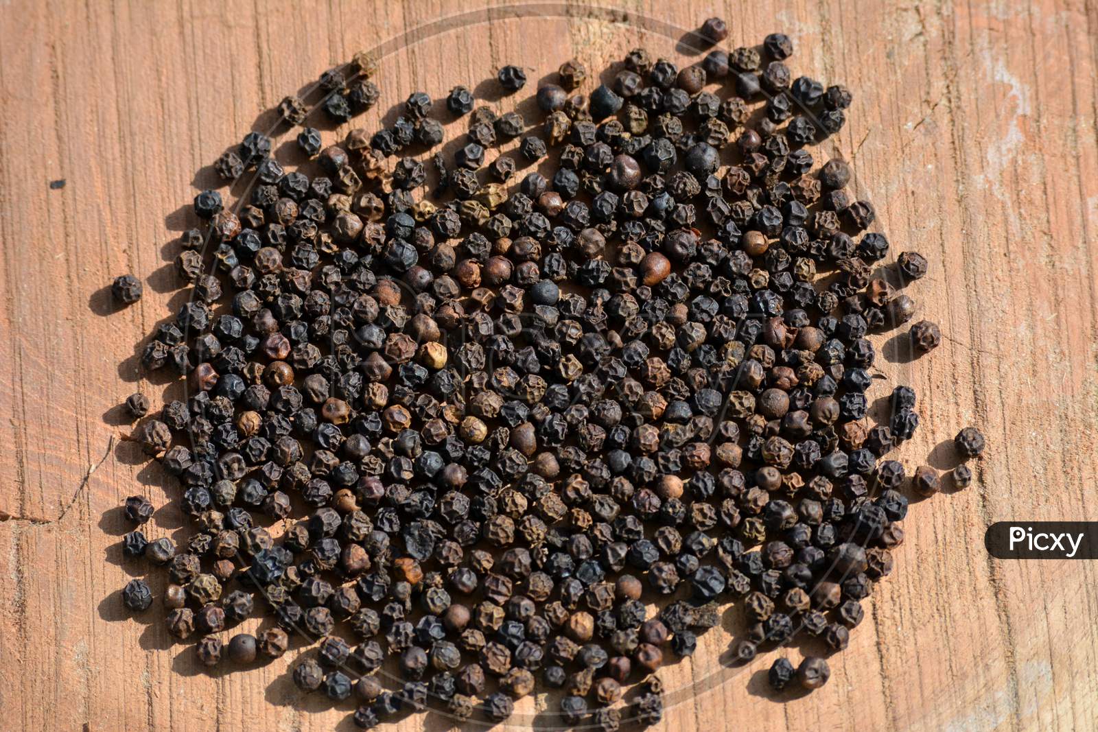 Black peppercorns on wooden background