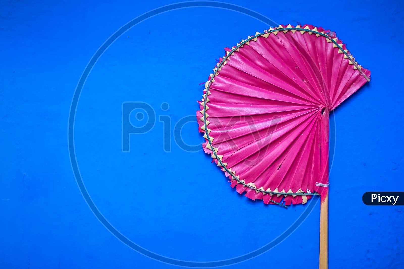 Palm Leaf Hand Fans Isolated With Blue Background. Handmade Pink Palm Leaf Hand Fans For Sell Available In Summer Season.