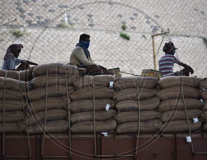 Workers Wearing Face Masks Sit Atop A Transport Vehicle Carrying Goods, During The Nationwide Lockdown, Imposed In The Wake Of Coronavirus, In Vijayawada.