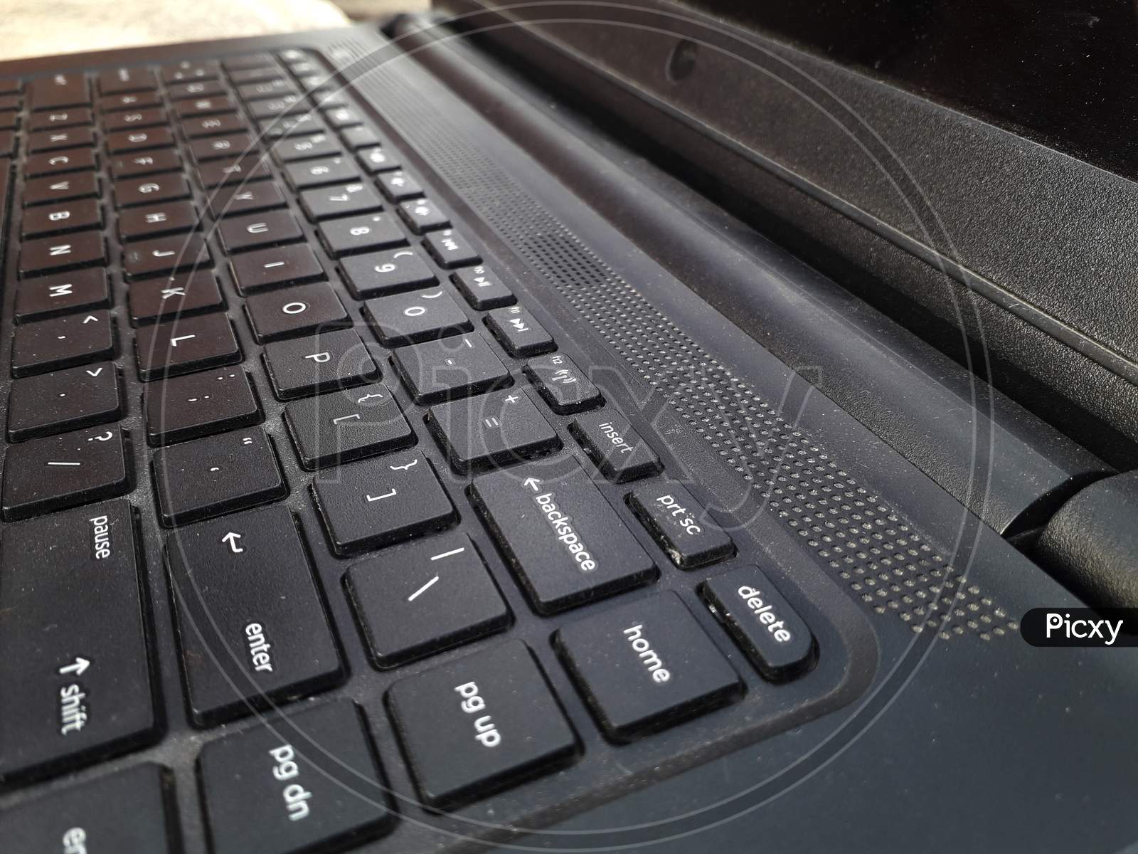Black colored laptop keyboard closeup side view near enter key