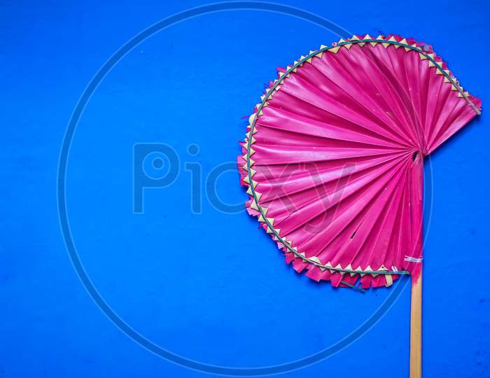 Palm Leaf Hand Fans Isolated With Blue Background. Handmade Pink Palm Leaf Hand Fans For Sell Available In Summer Season.