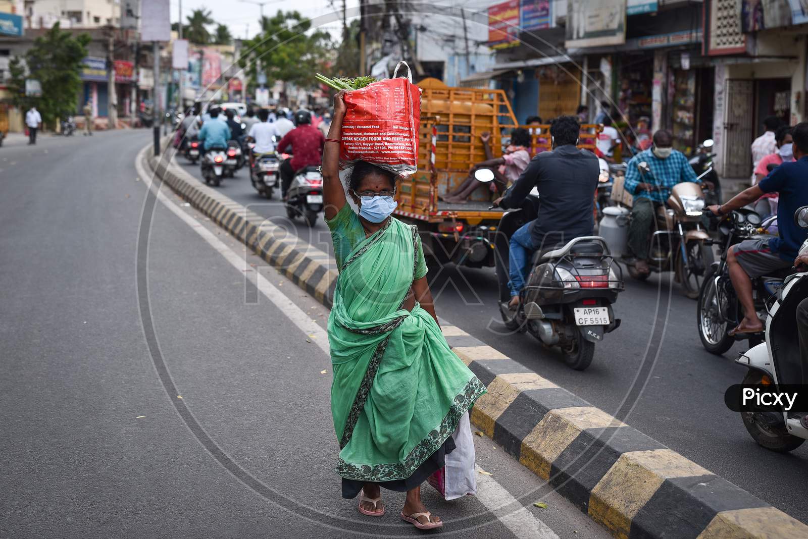 A Woman Wearing A Face Mask Walks With A Bag Of Vegetables Over Her Head During The Nationwide Lockdown Imposed In The Wake Of Coronavirus, In Vijayawada.