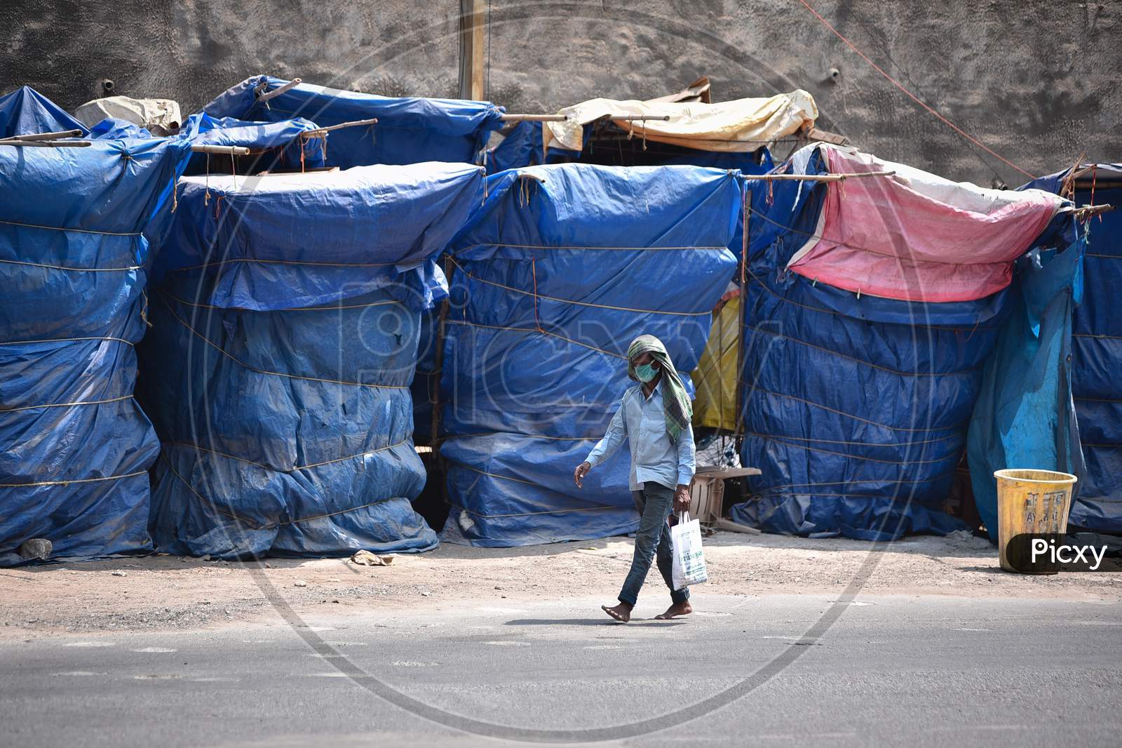 A Man Wearing A Face Mask Walks Past The Closed Roadside Stalls, Outside The Kanaka Durga Temple, During The Nationwide Lockdown, Imposed In The Wake Of Coronavirus, In Vijayawada.