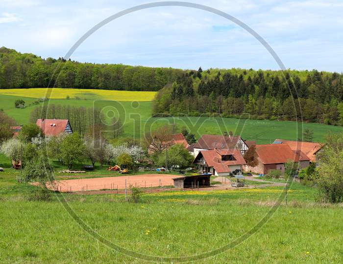 Small Village In Germany Surrounded By Green Fields.