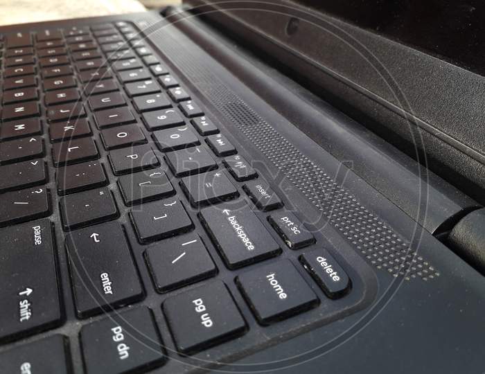 Black colored laptop keyboard closeup side view near enter key