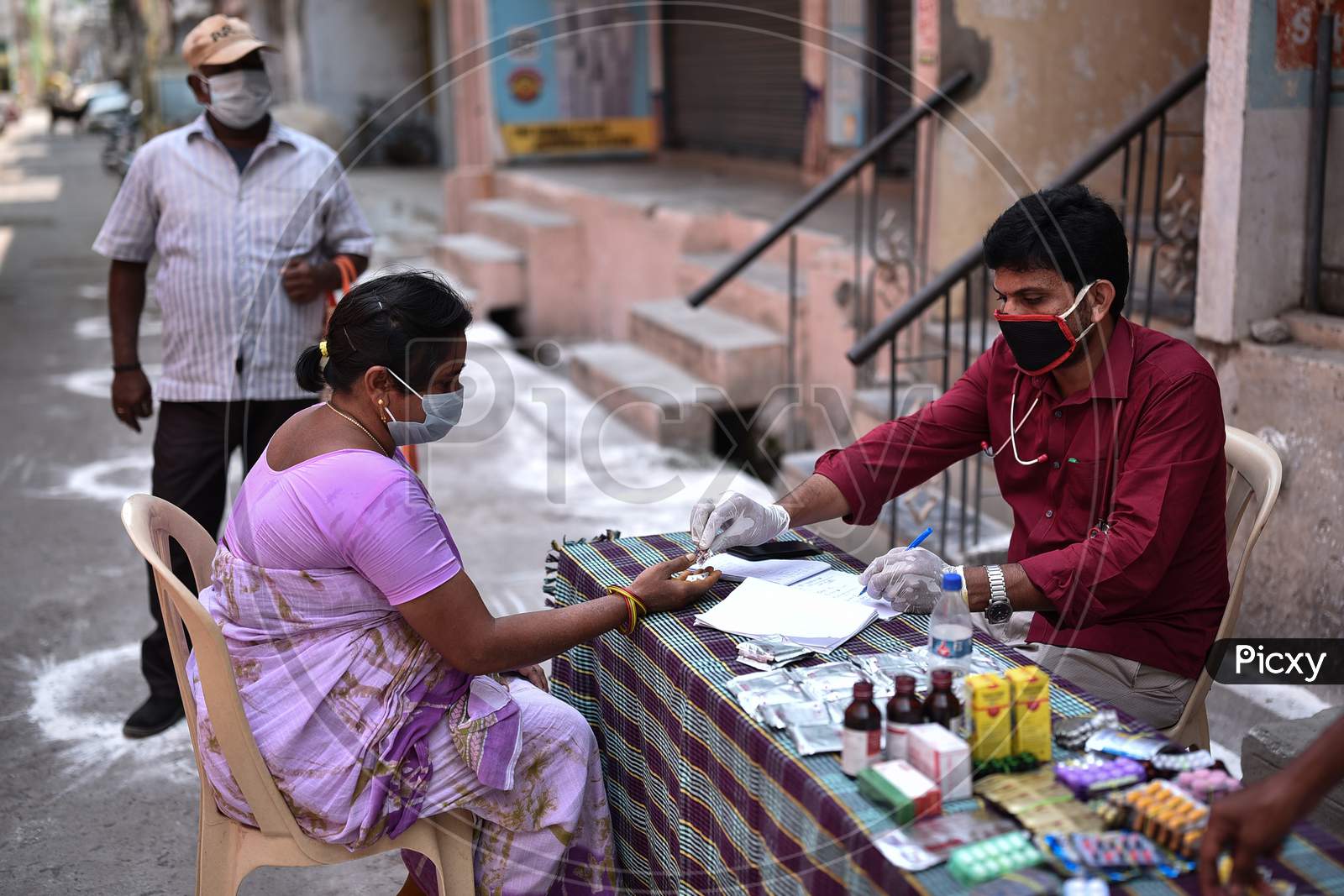 A Woman Receives Medicines From The Medical Staff, During A General Health Checkup At A Covid-19 Contaminated Zone Amid The Nationwide Lockdown Imposed In The Wake Of Coronavirus, In Vijayawada.