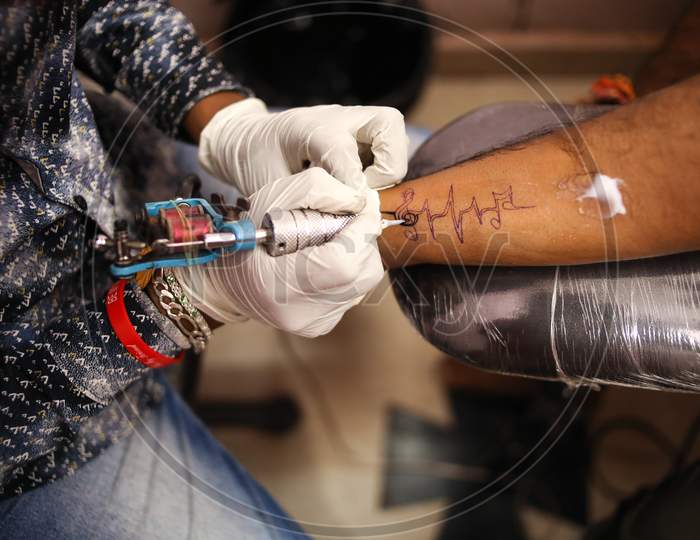 Tattoo artist drawing a musical note tattoo on a man forearm hand