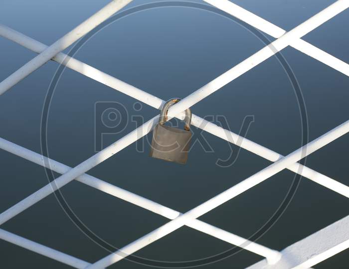 A Padlock Locked Around The Bridge Fence