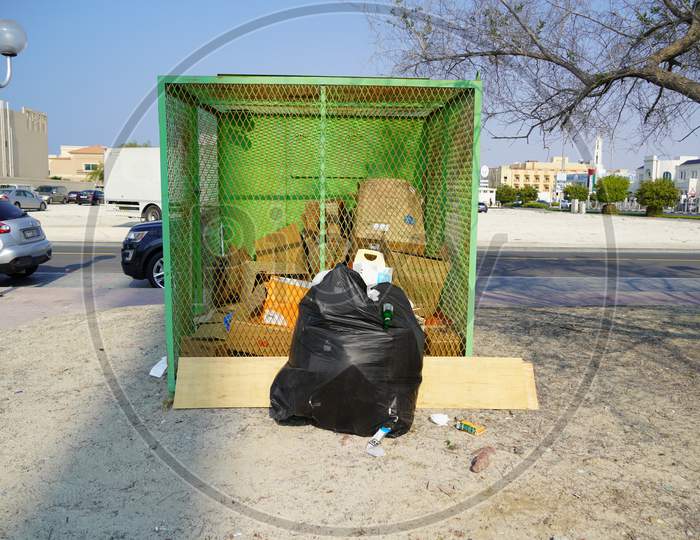 Dubai Uae December 2019 Overflowing Black Full Garbage Bag Isolated. Garbage Bags, Black Bin Bags. Environment And Object Concept. Lot Of Empty Cardboard Boxes At Back Side.Residential Area.