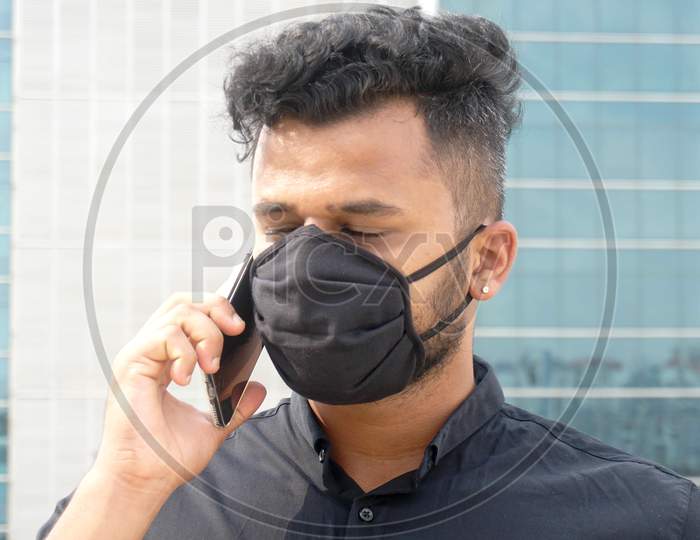 young masked businessman with mobile phone
