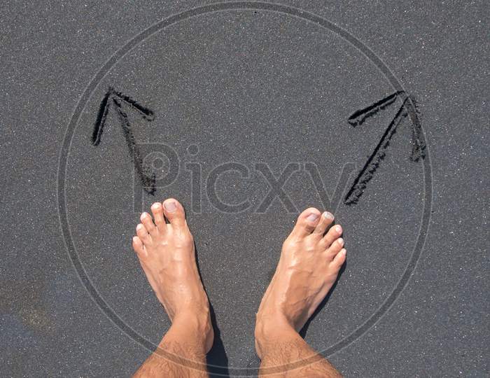 Male Feet Standing In Front Of Two Direction Arrows