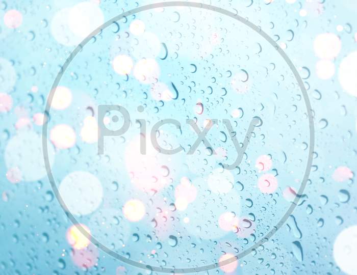 water drops on glass window with bokeh lights