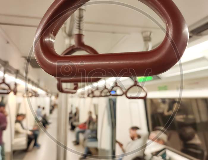 Close up of empty handrails in a Delhi metro train, Handle hand straps in public transportation for passenger safety. Brown hanging handhold for standing passengers in a modern metro train.