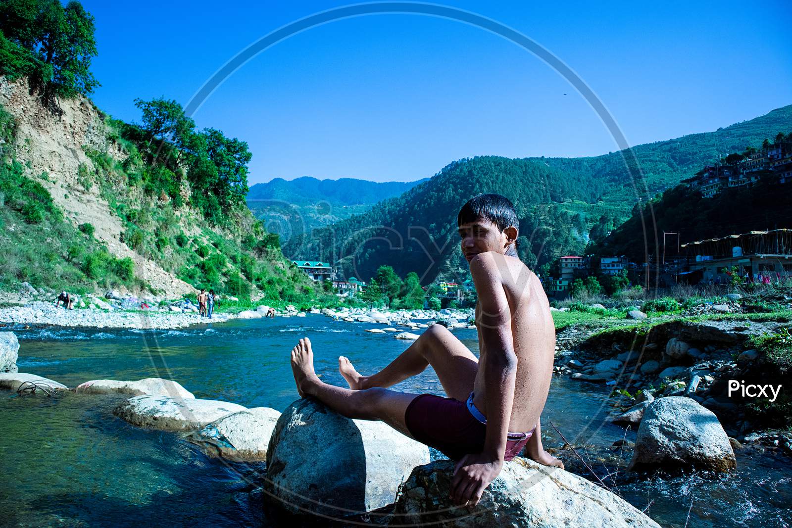 Nerwa, Himachal Pradesh, India - July 20Th, 2019: Young Boy Sitting On A Rock Near Flowing River