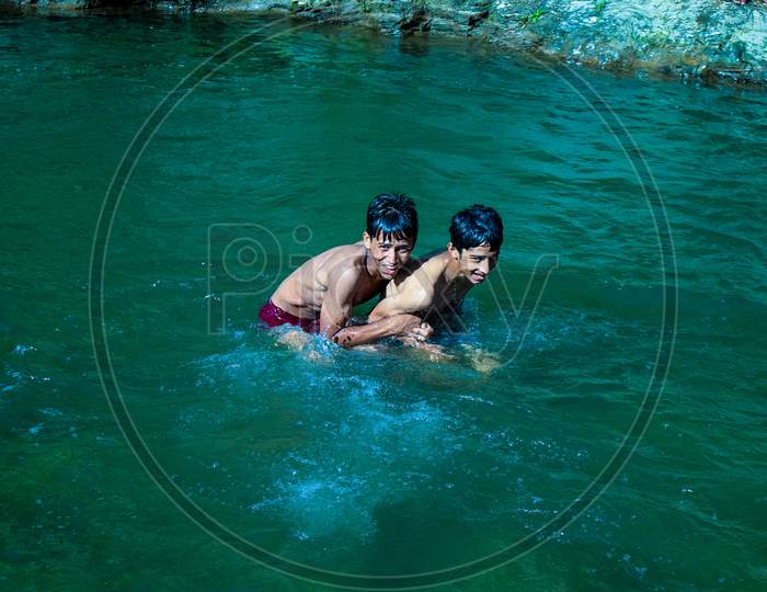 Nerwa Village, Himachal Pradesh, India - July 20Th, 2019: Young Indian Boys Having Fun Swimming In The Fresh River Water. Summer Vacation Concept