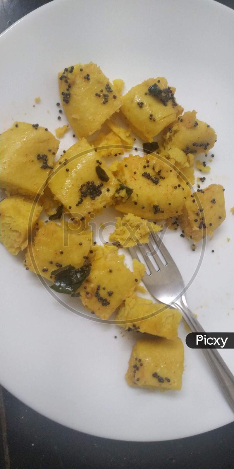 Indian Gujrati Famous Street Food Dhokla With Mustard Seeds In White Plate With Fork